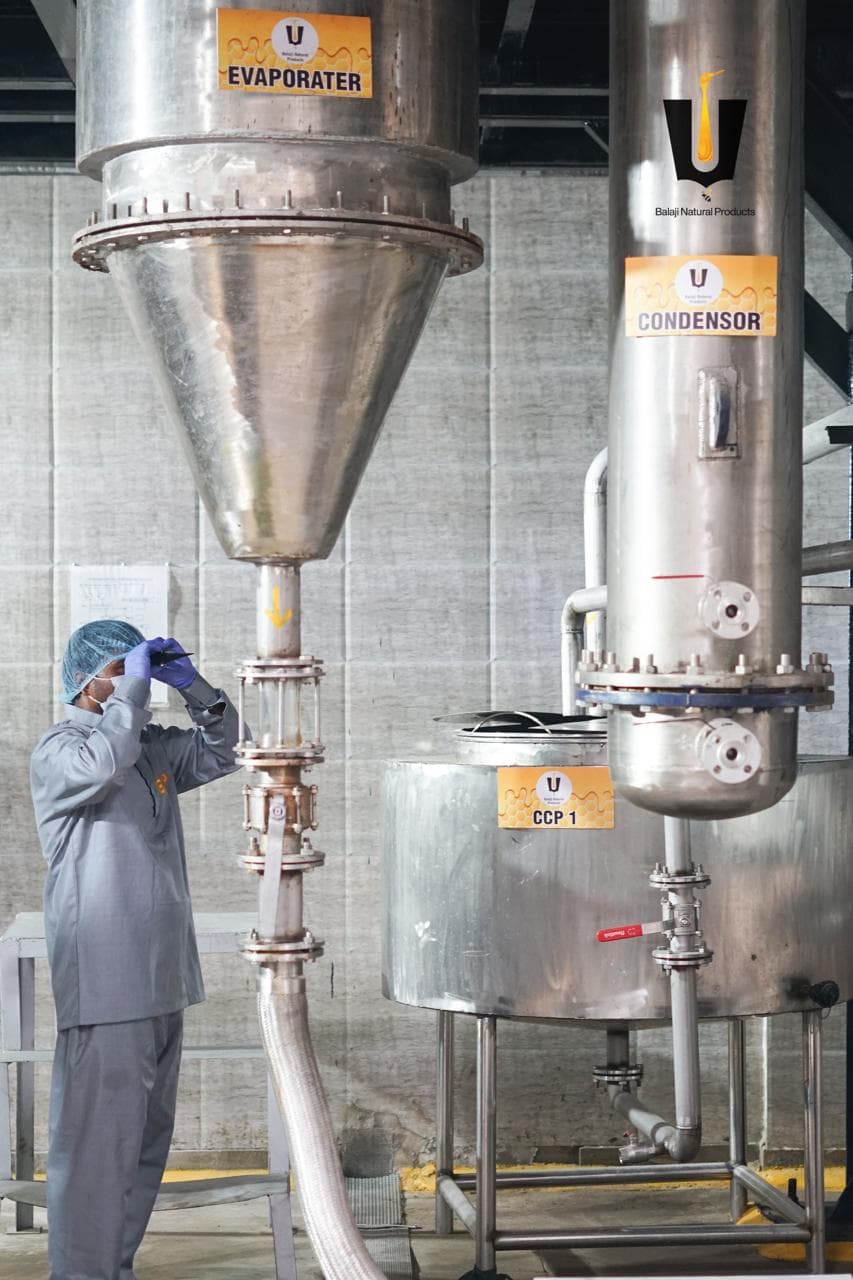 Technician checking honey flow at a sight glass under evaporator, condenser, and CCP 1 tanks