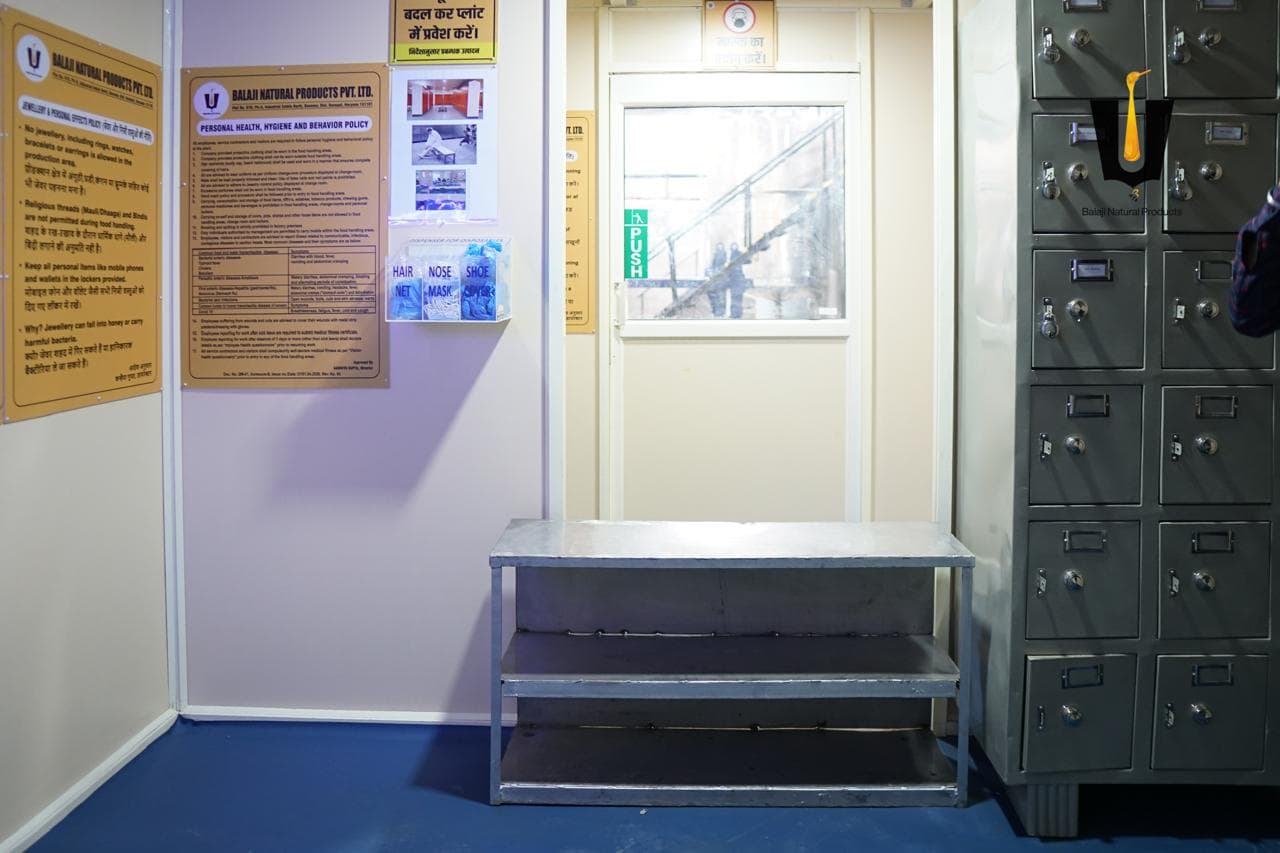 Changing-room lockers, shoe rack, and hair-net, mask, and shoe-cover dispenser before the production floor