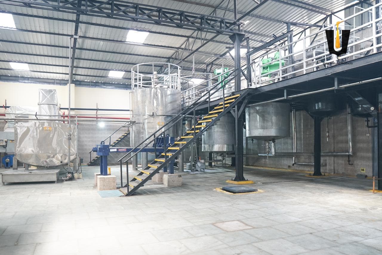 Wide view of the honey processing floor with stainless tanks, insulated vat, and upper-level pumps